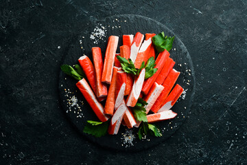 Crab sticks from a crab on a black stone plate. Rustic style. Seafood delicacies. © Yaruniv-Studio
