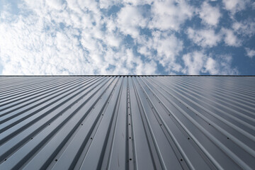 View upwards to the facade of a warehouse with a cladding of silver corrugated aluminum sheet.