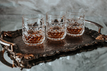 Three expensive glasses of whiskey on an old metal tray.