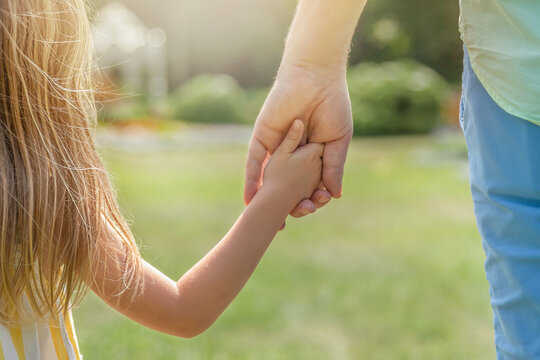 Dad and daughter are walking outdoors and holding hands. The concept of reliability, trust. closeup. Happy family
