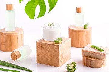 Natural cosmetics with aloe vera on wooden podiums in reusable bottles