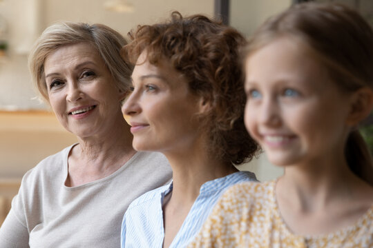 Head shot portrait close up of smiling beautiful mature woman posing with adult daughter and adorable little granddaughter, happy three generations of women standing in row, growing process
