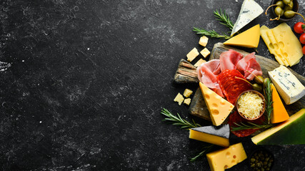 Italian appetizers. Cheese, wine, salami and prosciutto on a black stone background. Top view. Free space for your text. - obrazy, fototapety, plakaty