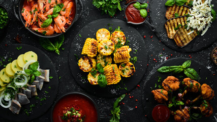 Set meal of meat, seafood and vegetables on the black stone table. Top view. Free space for your text.