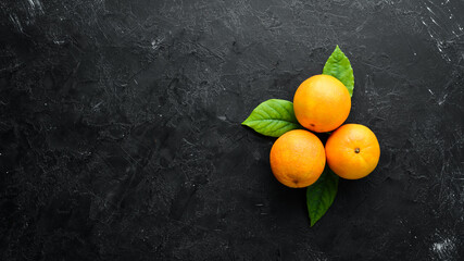 Fresh oranges with leaves. Citrus fruits on stone background. Top view. Free copy space.