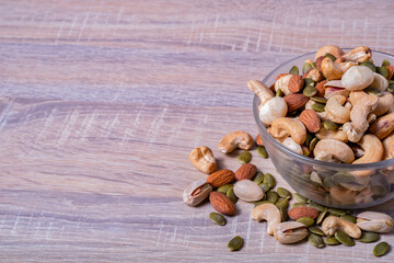 Many type of mix nuts in a bowl on wooden table. Vegetarian or vegan snake. Healthy food eating.