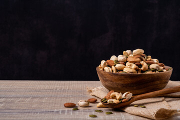 Many type of mix nuts in a bowl on wooden table. Vegetarian or vegan snake. Healthy food eating.