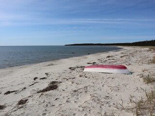 Lonely fishing boat ashore an empty Baltic coastline white sandy beach