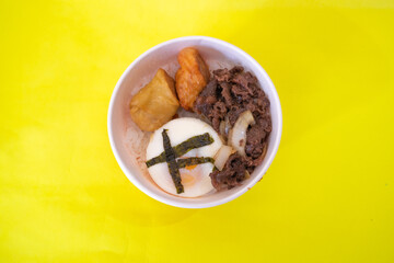 This is a bento, contains white rice, yakiniku, shrimp roll and egg