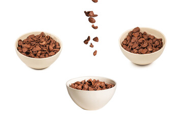 Chocolate corn flakes falling to the white bowl isolated on white. Motion.