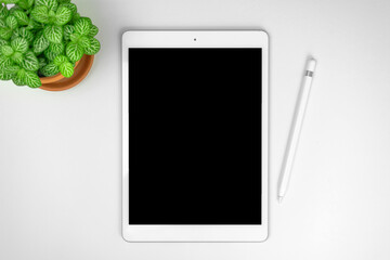 Minimalist workspace concept background with tablet mockup and stylus pen on a silver gral desktop with green plant, top view and copy space photo