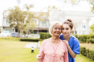Happy elderly woman with a caregiver in the garden, Senior woman with nurse or doctor. Home care concept..