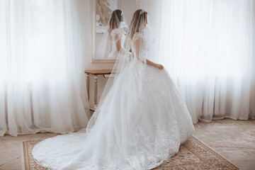 Fototapeta premium Beautiful young bride with light make-up in white dress in an exquisite interior 
