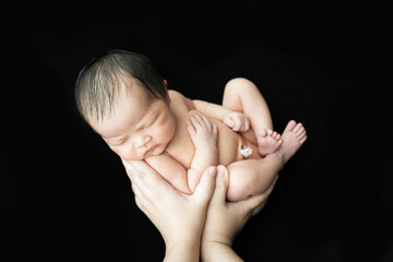 Obraz na płótnie Canvas Cute Baby Newborn Sleeping on Parents Hands, New Born Kid Sleep in Family Hand, on a black background.