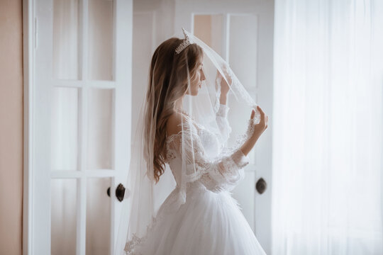 Beautiful brunette bride with light make-up in white dress  in an exquisite interior 