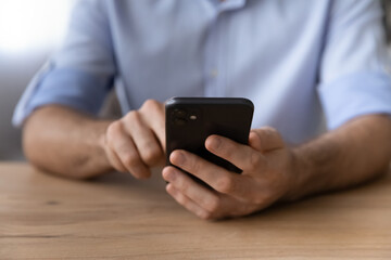 Working on cell. Close up shot of new modern gadget smartphone in millennial businessman hands. Young male sit at workplace desk use mobile phone device make call surf data online text message in chat