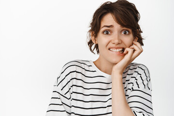 Anxious brunette woman biting fingers, looking scared, frightened about something, look nervous,...