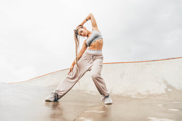 Fototapeta na wymiar Fit woman dancing modern dance on skate park.