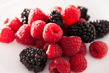 handful of raspberry and blackberry berries on white background