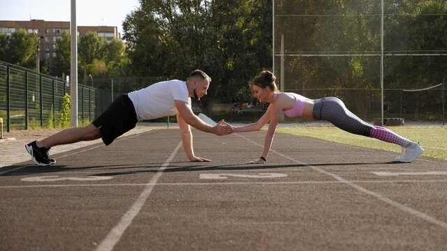 Sports active man and women train in the summer outdoors in a public stadium.