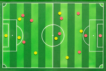 High angle shot of a soccer game strategy with red and yellow colored circular field and figures on a blackboard.