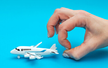 Woman's hand with airplane toy on blue background. Close up.