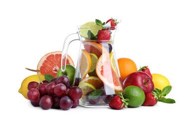 Glass jug with different whole and cut fruits on white background