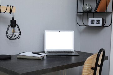 Comfortable workplace with modern laptop near light grey wall indoors. Space for design
