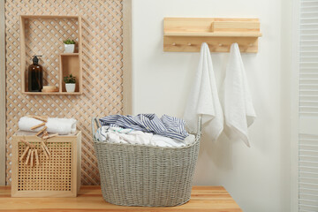 Fototapeta na wymiar Wicker basket with dirty laundry on wooden table in bathroom