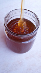 honey flowing into a glass jar on a light background