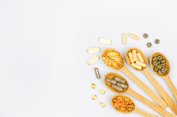 A variety of dietary supplement pills in wooden spoons, top view with copy space. Health care concept