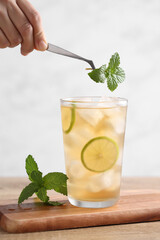 Food stylist use tweezers decorating iced tea with lemon