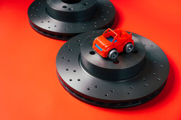 A pair of new automobile brake discs with little toy car.