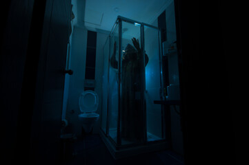 Horror silhouette of woman in window. Scary halloween concept Blurred silhouette of witch in bathroom