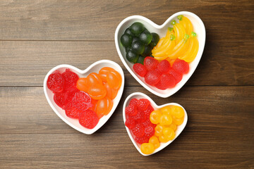Fototapeta na wymiar Delicious gummy fruit shaped candies on wooden table, flat lay