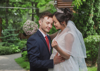 Portrait of an international loving couple of newlyweds against the backdrop of nature and flowers