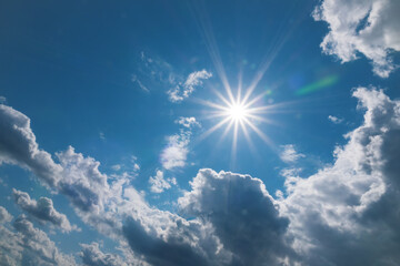 Sparkle sun shining above fluffy clouds. Beautiful sky background with lens flare.
