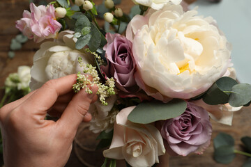 Florist creating beautiful bouquet at table, top view