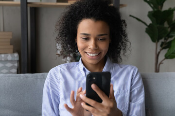 Smiling African American woman look at smartphone screen have webcam digital virtual event online....
