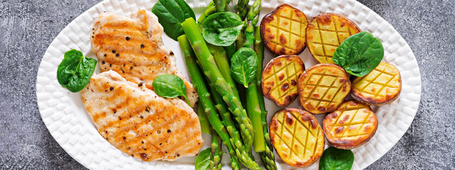 Chicken fillet cooked on a grill with a garnish of asparagus and baked potatoes. Dietary menu. Healthy food. Flat lay. Top view