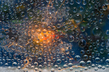 Transparent spheres are illuminated by a flash of orange-red light and are located against a dark green-blue background. Space abstraction. 3D render.