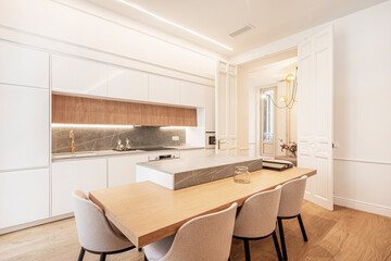 Oak and gray marble table on white American-style kitchen island with white tones and light wood in vacation rental apartment