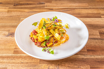 Beef sirloin tartare with slices of potatoes and fried egg with sprouts of fresh vegetables