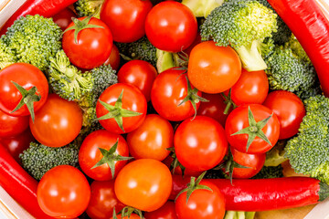 Top view image of bulk cherry tomatoes, raw broccoli chunks and hot red chili peppers