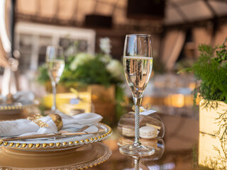 Exclusive decoration of the banquet table on the terrace in the luxury restaurant. A glass of expensive champagne on a gilded chair.