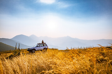 Person enjoying sunset on top of 4x4 vehicle in the mountains of the Nationalpark Sharr, Brezovicë, Kosovo - obrazy, fototapety, plakaty