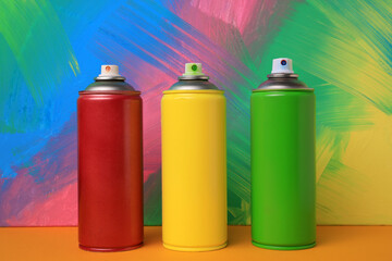Cans of different spray paints on color background. Graffiti supplies