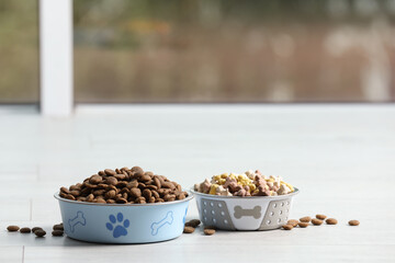 Bowls with dry dog food on white floor indoors