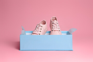 Pair of stylish canvas shoes in box on pink background