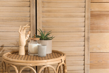 Stylish table with decor and houseplant near wooden wall, space for text. Interior design